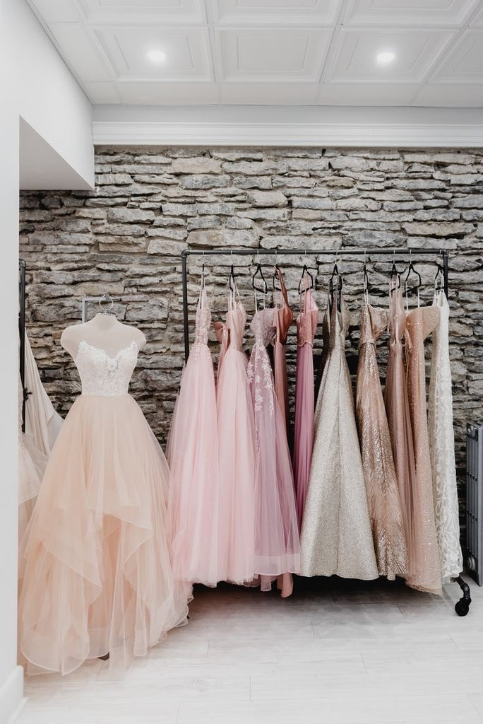 A rail of dresses in a prom shop and one dress on a mannequin
