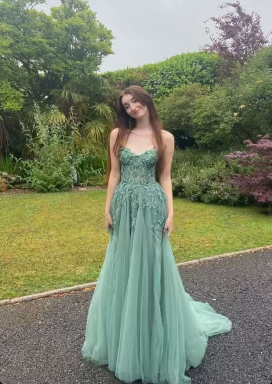YLONA Prom Dress in with a lace corset top and flowing tulle skirt, worn with detachable straps and floral detailing on a red carpet.