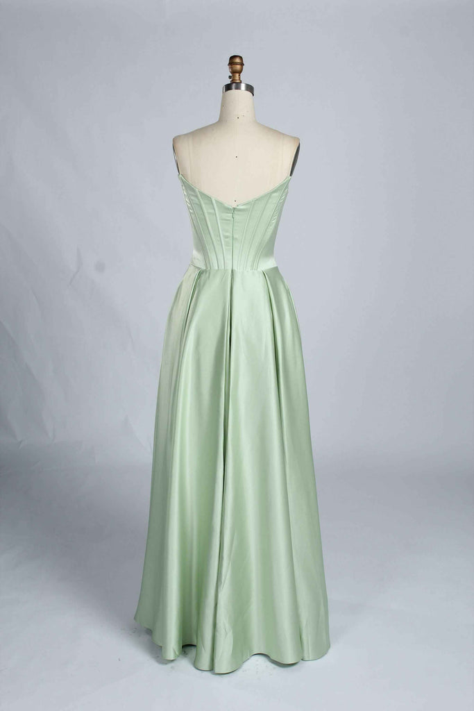 Back view of sage green Jessica Stuart Darcet Prom Gown with V-back corset and full-length pleated skirt.