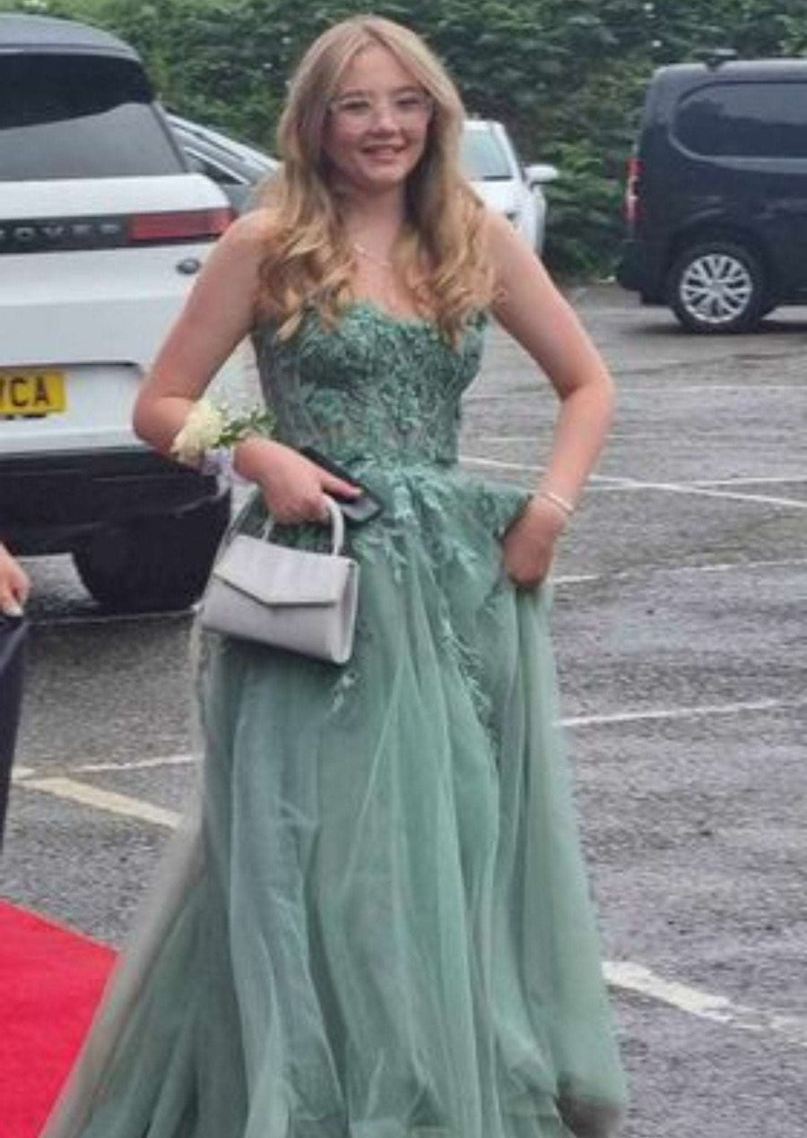 YLONA Prom Dress in with a lace corset top and flowing tulle skirt, worn with detachable straps and floral detailing on a red carpet.