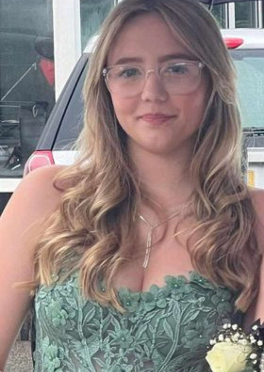 YLONA Prom Dress in with a lace corset top and flowing tulle skirt, worn with detachable straps and floral detailing on a red carpet.