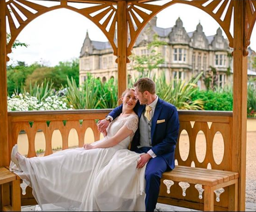 Groom wearing Sherbet Lemon Wedding Tie with navy suit beside bride in gazebo. Elegant wedding accessory for stylish groomsmen looks.