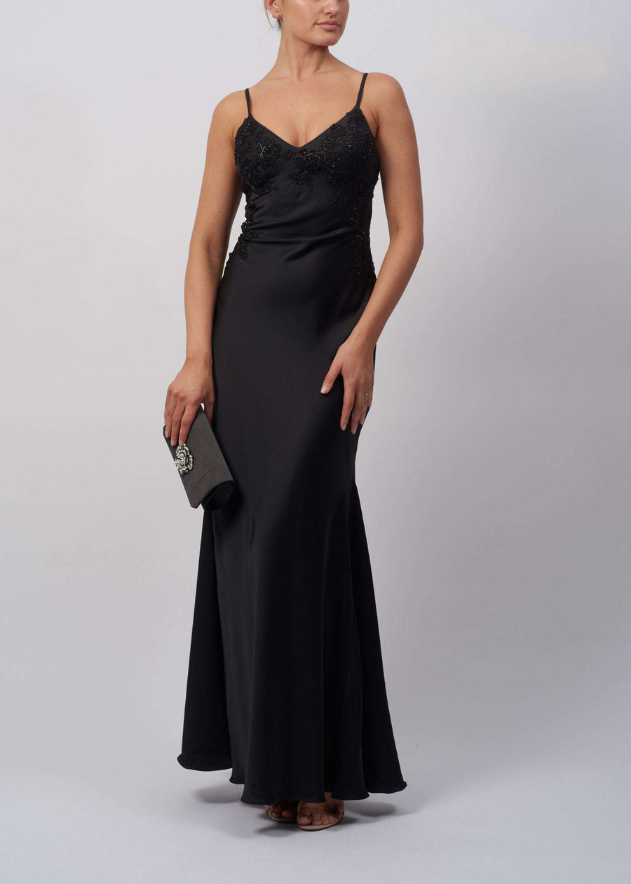 Model wearing a black satin slip embellished long gown by Mascara London, featuring a sleek, fitted design with a graceful silhouette