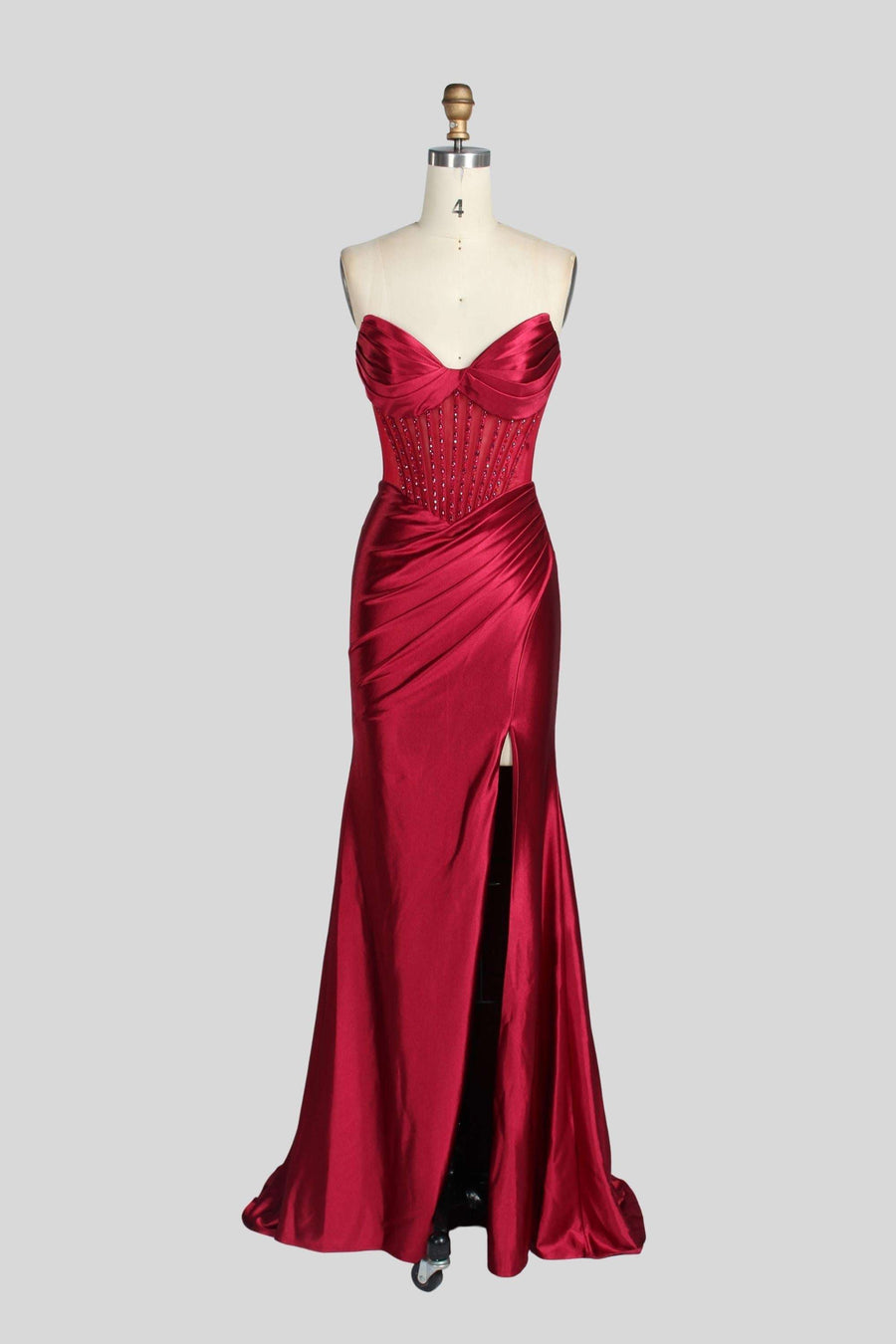 Jessica Stuart Strapless Wine Gown displayed on mannequin with mermaid silhouette, crystal-embellished bodice, and satin fabric for prom or gala nights.