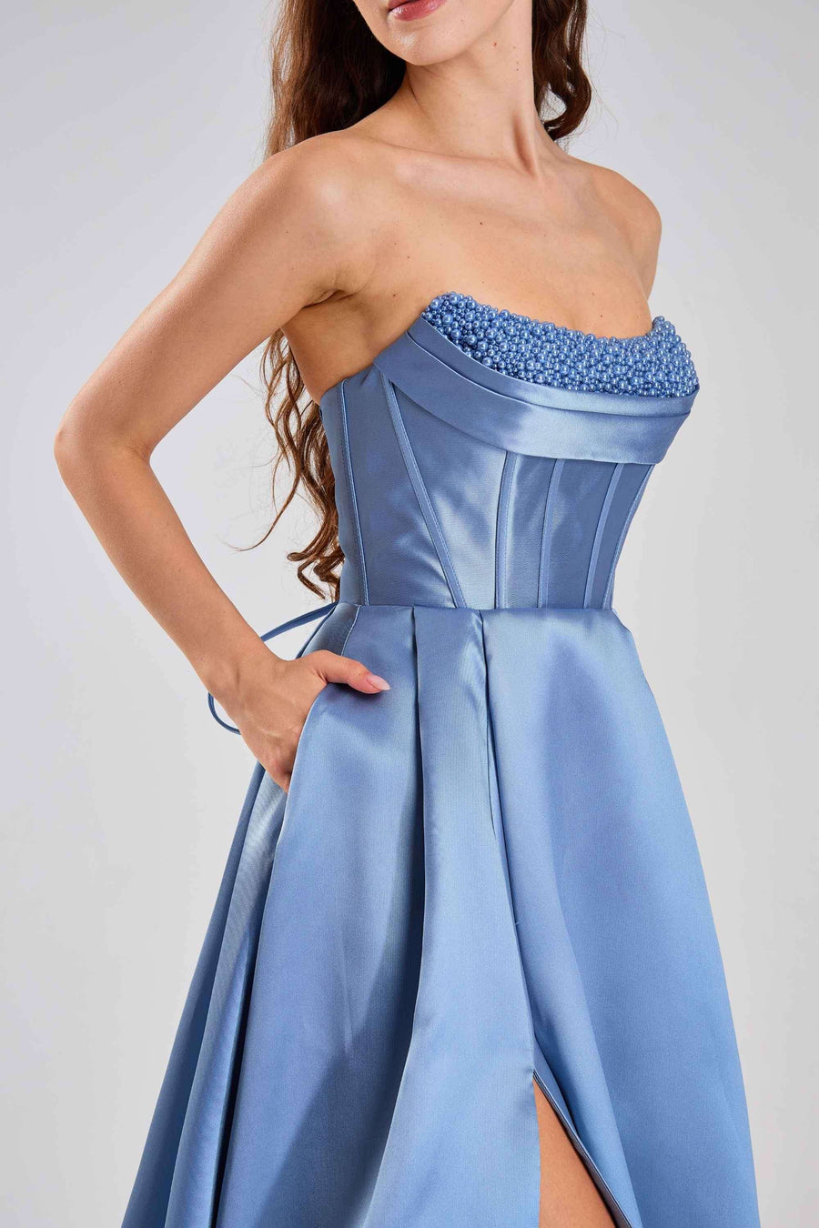 Jessica Stuart Steele Blue Pearl Evening Gown 33219B featuring a satin corset bodice with pearl embellishments and a high-slit pleated skirt.