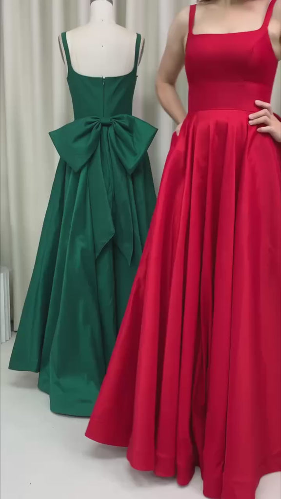 Video of a lady wearing a Red ball gown with pockets and big bow. Same dress in green at the background
