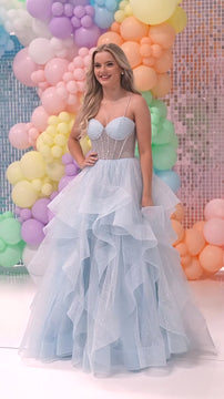 Woman in blue prom dress with layered tulle skirt at pastel balloon and mosaic backdrop