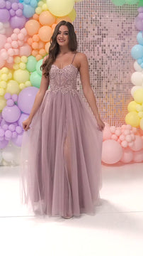 Young woman in pink embroidered prom dress with colorful balloon backdrop