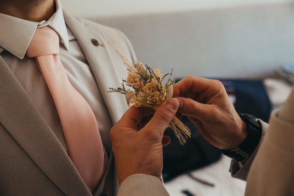 Groom wearing a Vintage Rose Wedding Tie while a boutonniere is pinned, showcasing the tie’s elegant tone against a beige suit.