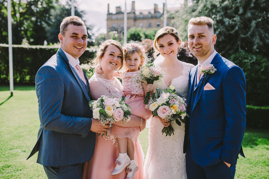 Family wedding photo with groom in Vintage Rose Wedding Tie, complementing the bride’s gown and pastel floral arrangements.