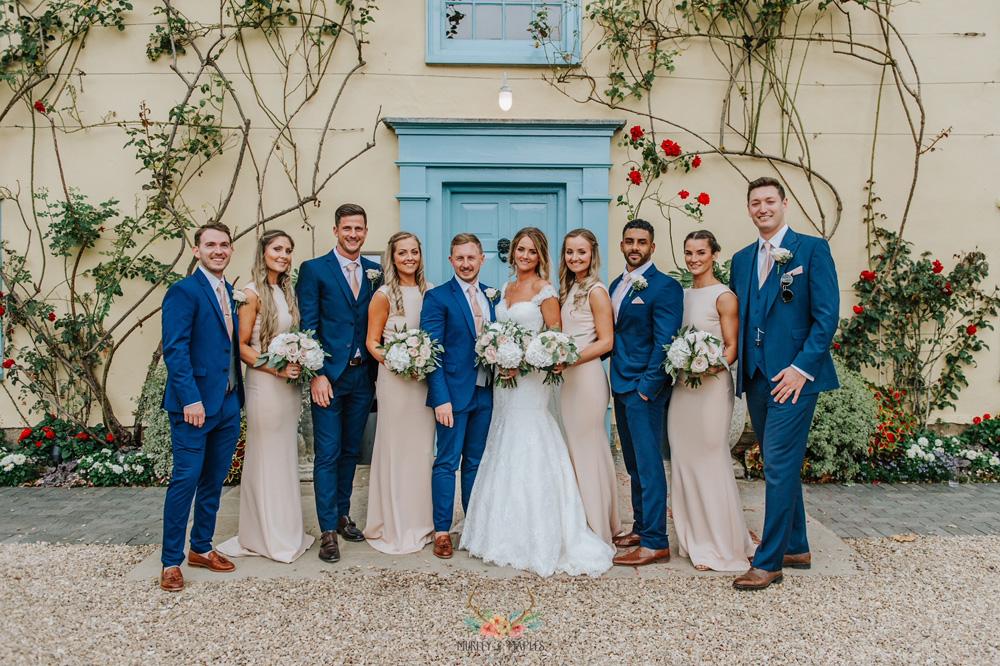 Bride and groom with wedding party in blush and navy attire, featuring Vintage Rose Wedding Ties for a soft romantic color palette.
