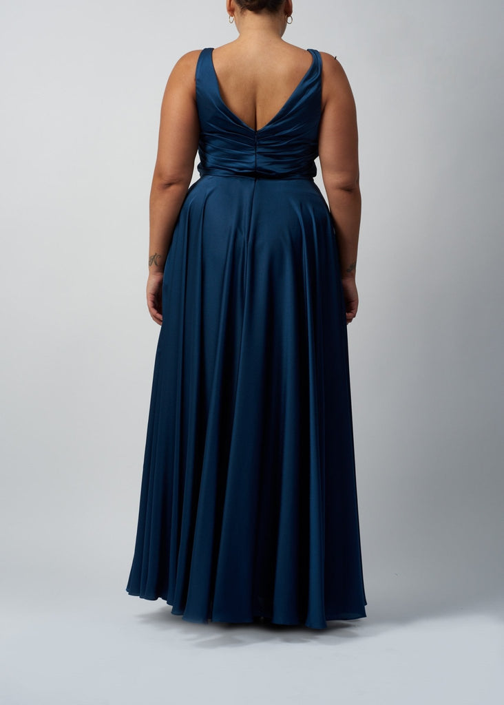 back view of plus size lady wearing dark blue wrap top satin ball gown dress