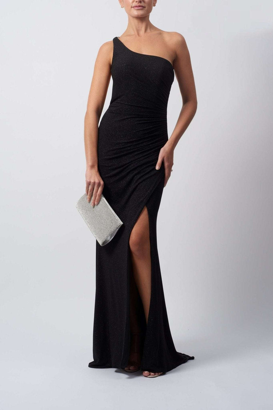Model wearing a black one-shoulder diamond strap jersey dress by Mascara London, featuring a fitted design with a high slit on the left leg.
